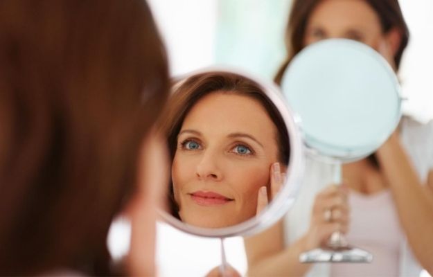 a woman happily looking into the mirror | 5 Ultherapy Benefits For Looking Younger