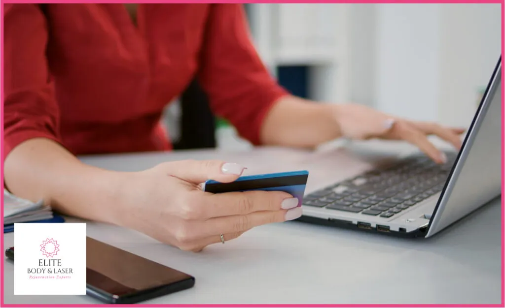 Image of a woman sitting at a computer, entering credit card information for payment. She is focused on the screen, typing details into the secure payment form to complete a transaction.