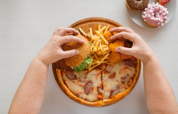 hamburger and fries placed on dish with donuts aside | Why can’t I lose weight even when I am eating less? | Why Can't I Lose Weight!? | 6 Stubborn Weight Loss FAQs