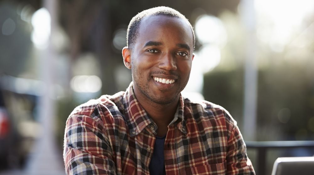 a smiling man wearing checked shirt | Hormone Replacement Therapy For Men | feature