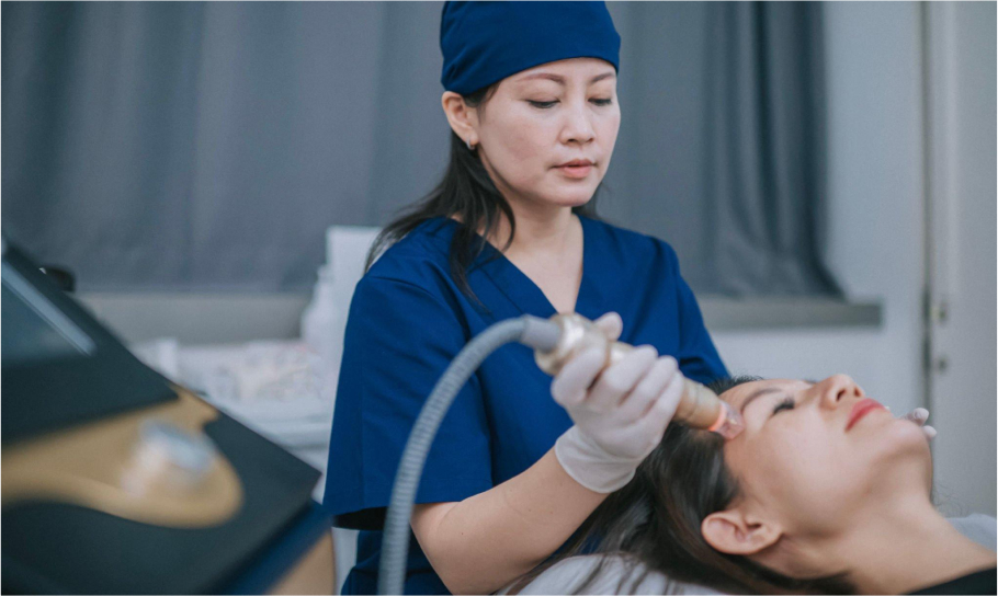 esthetician doing a laser hair removal on the forehead of patient