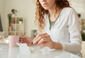 Woman organizing weekly pills in a medication planner for health management