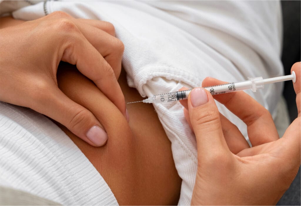 Close-up of woman self-injecting weight loss medication in abdomen